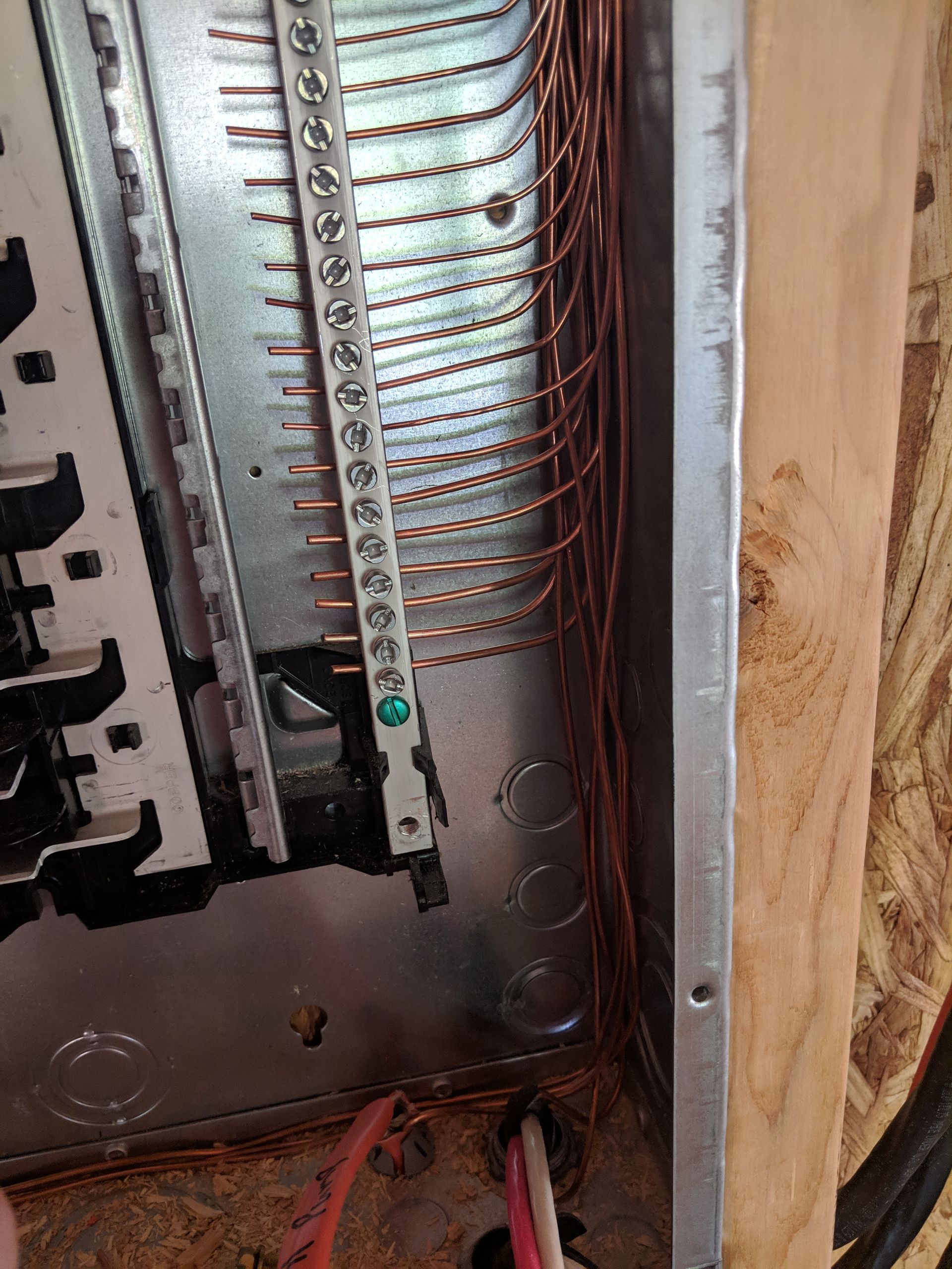 Electrical panel with multiple copper ground wires connected to a ground bar.