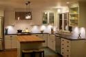 Modern kitchen with wooden island, white cabinets, and warm pendant lighting