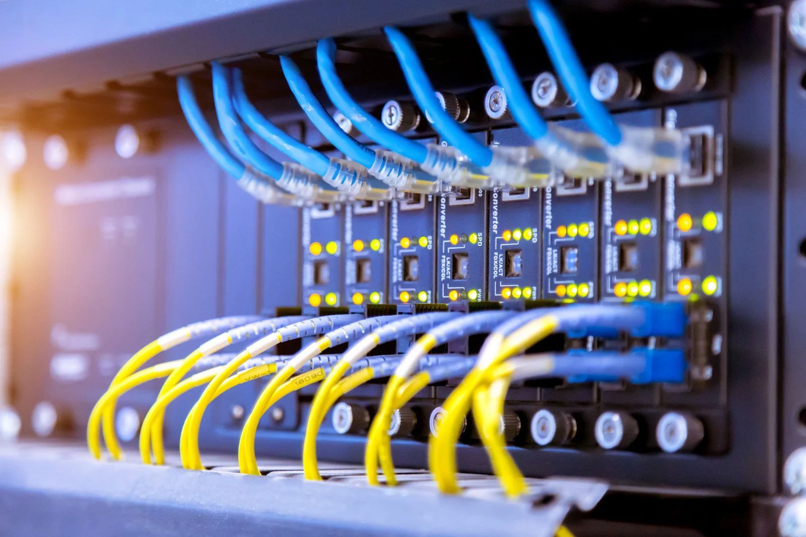 Close-up of network server ports with blue and yellow Ethernet cables connected
