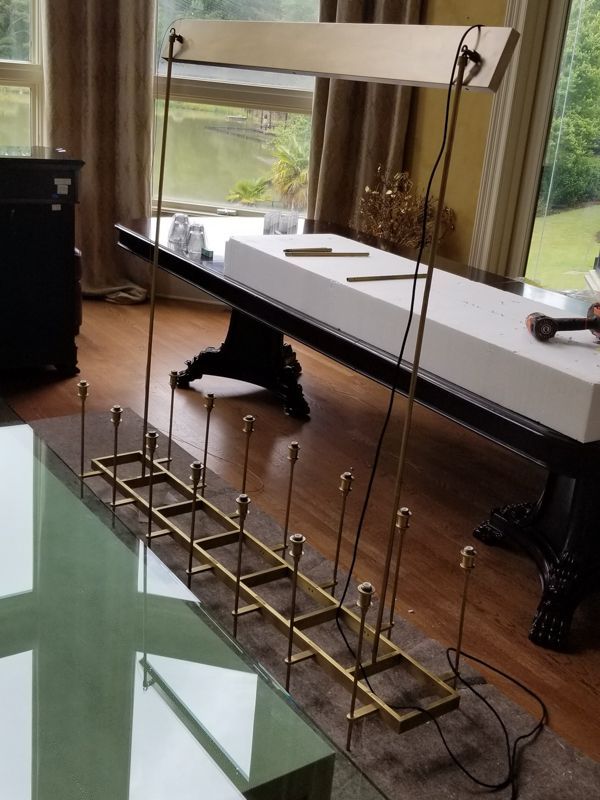 Long rectangular metal framework on a floor beside a large window, with wires and black support legs.
