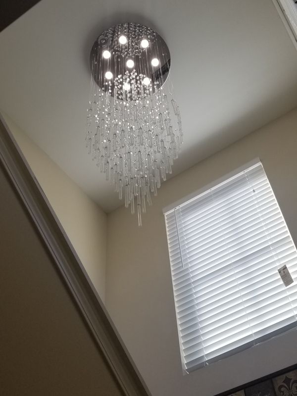Crystal chandelier on a ceiling in a room beside a window with white blinds.