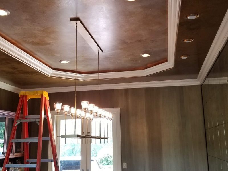 Ceiling under construction with ladder, hanging light fixture, and recessed trim in a room