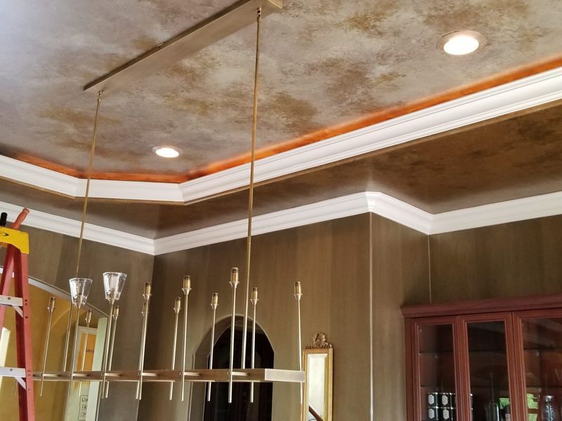Ceiling with recessed lights, crown molding, and a hanging chandelier in a wood-paneled room