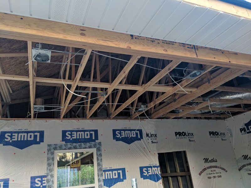 Partially finished room with exposed wooden ceiling joists and insulated walls under construction