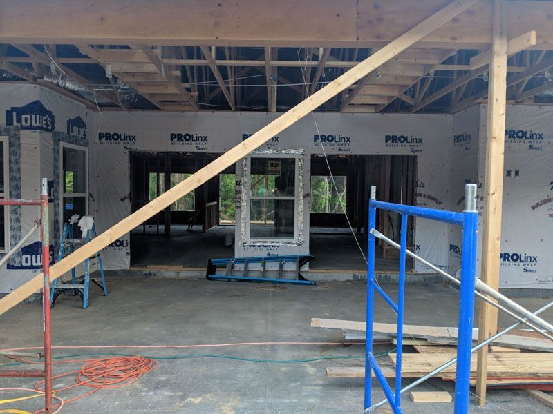 Interior construction site with blue scaffolding, wooden braces, and exposed framing under ceiling joists.