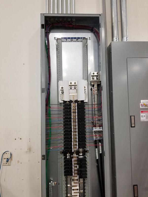 Open electrical breaker panel with rows of switches in a utility room