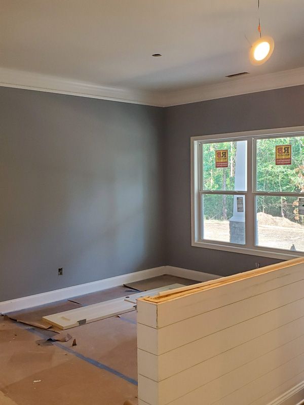 Empty room with gray walls, large window, and a partially built white half-wall.