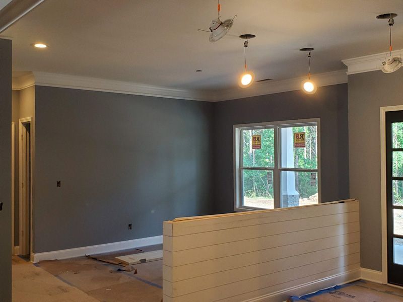 Empty room under renovation with gray walls, hanging light bulbs, and a half-built white partition.