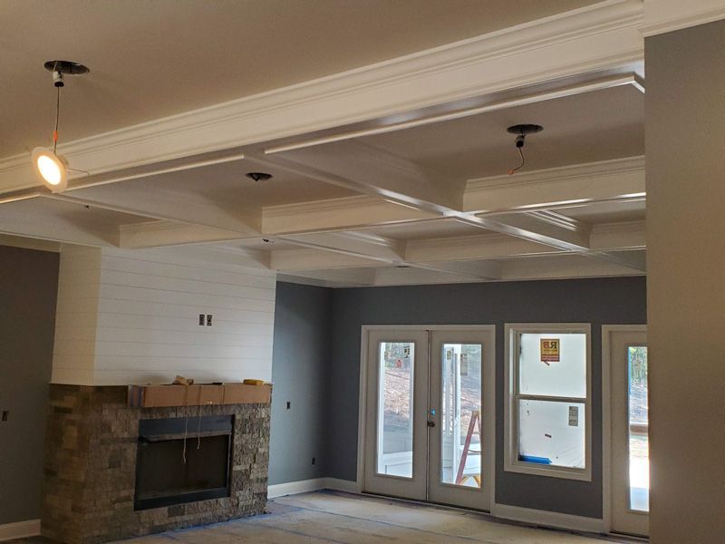 Empty living room with a stone fireplace, tray ceiling, and French doors leading outside