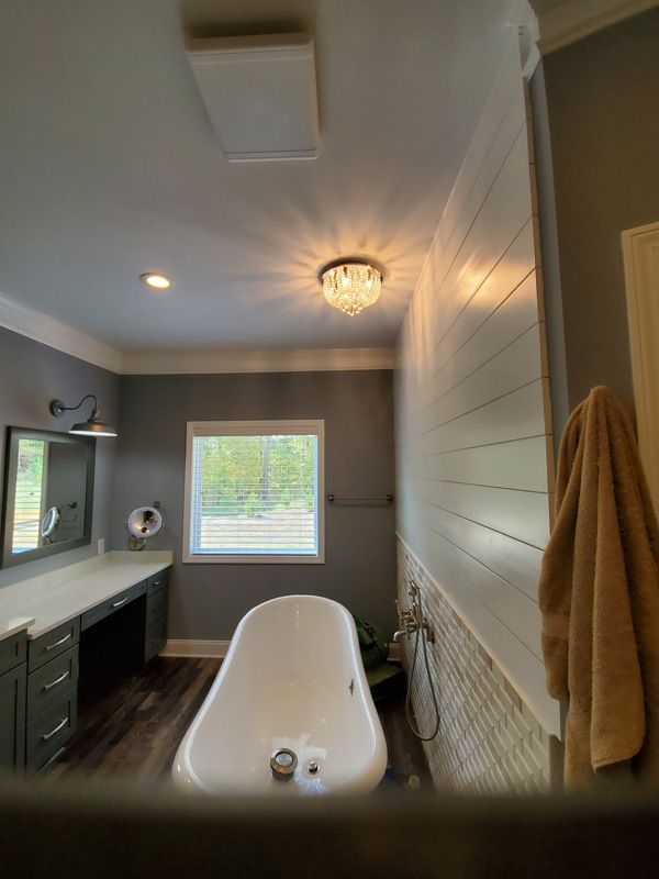 Modern bathroom with a freestanding tub, vanity, window, and shiplap accent wall