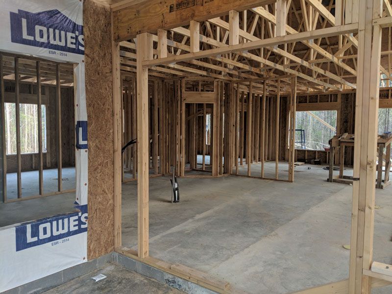 Framed house interior under construction with exposed wood studs and concrete floor