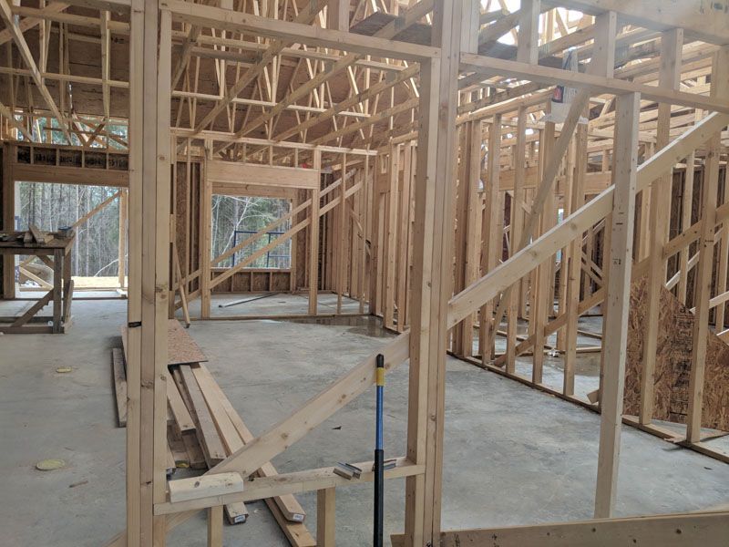 Framed house interior under construction with exposed wooden studs and a concrete floor