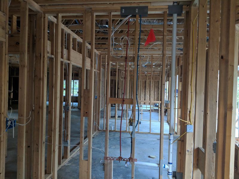 Interior of a framed house under construction with exposed wood studs and ceiling joists