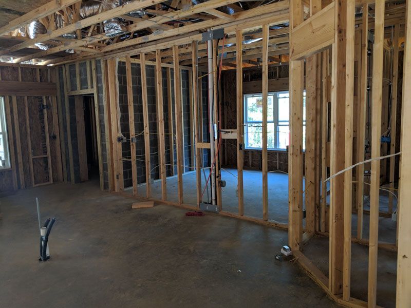 Unfinished interior with exposed wooden framing, plumbing, and a window in a construction site