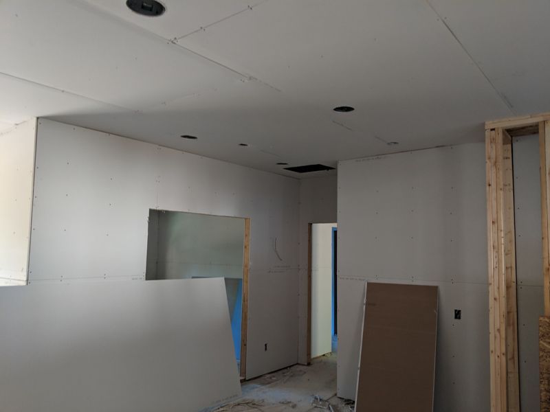 Unfinished interior room with drywall, exposed framing, and a partially open doorway.