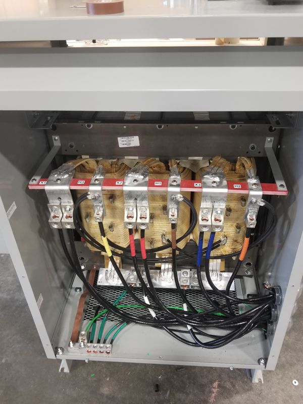 Open electrical panel with multiple transformers, wiring, and circuit components.
