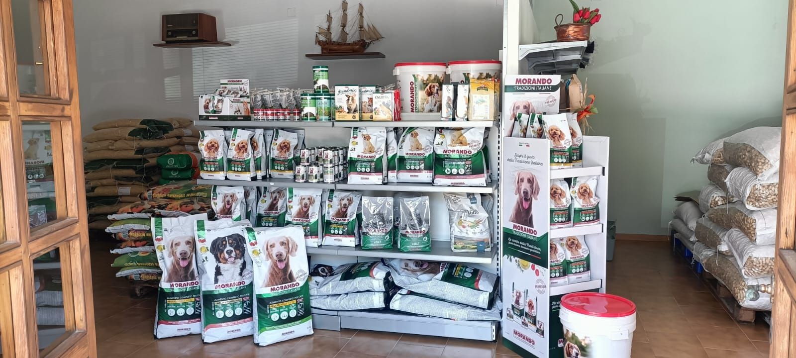 Espositore per alimenti per animali domestici con sacchetti e scaffali all'interno di un piccolo negozio.