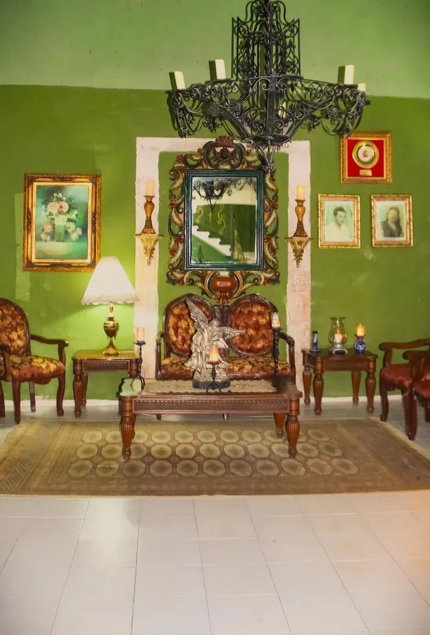 Living room with antique furniture, green walls, ornate chandelier, and artwork.