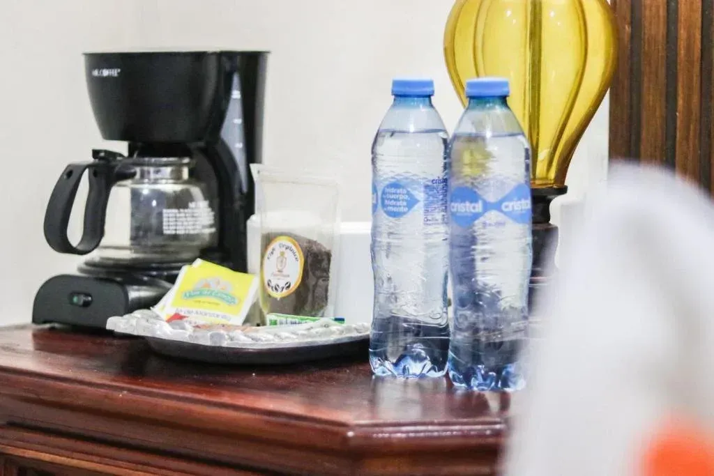 Cafetera, botellas de agua y juego de té sobre una mesa de madera oscura.