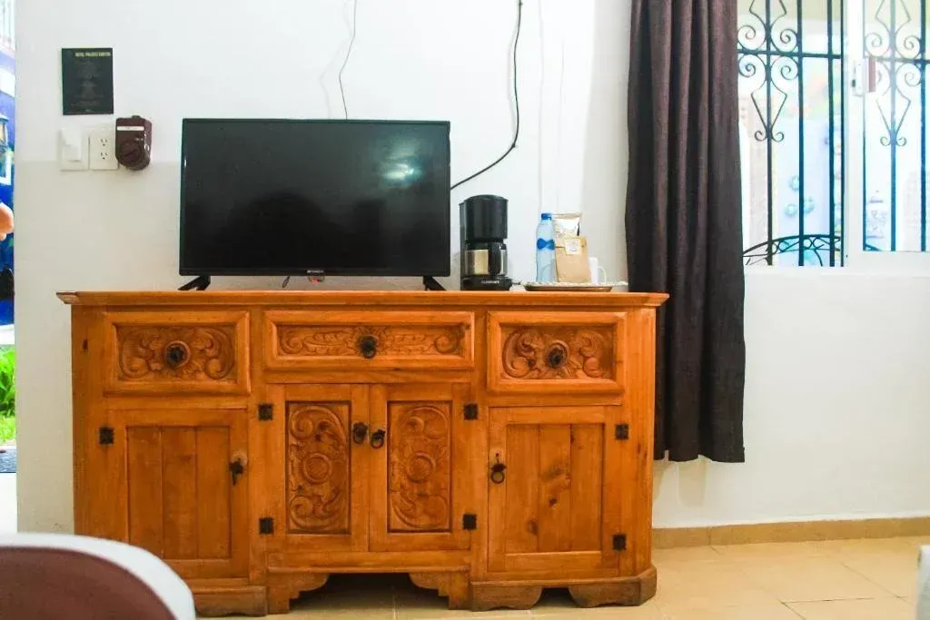Wooden cabinet with a TV and coffee maker; a window with brown curtains.