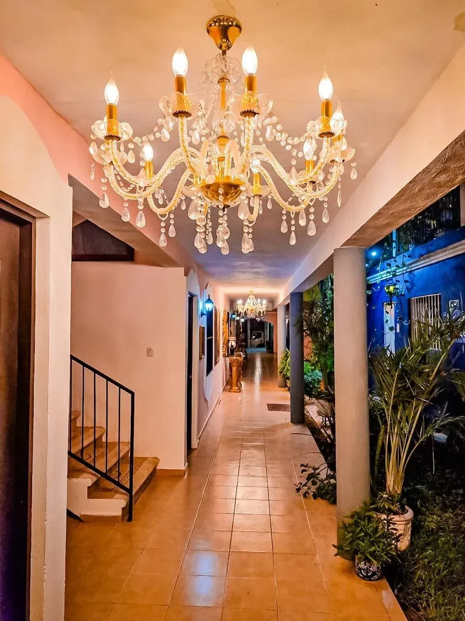 Hallway with chandelier, stairs, tile floor, and an outdoor view.
