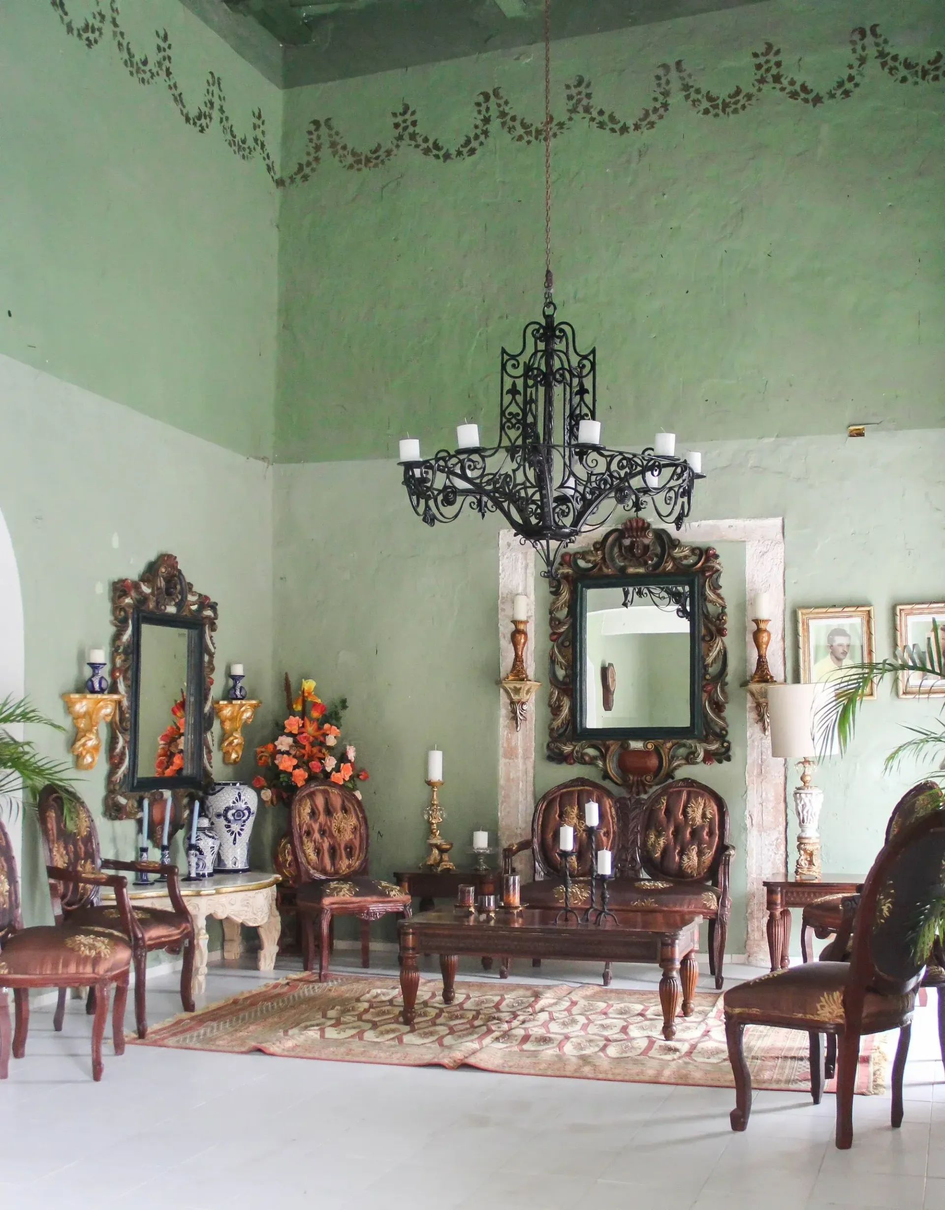 Ornate room with green walls, antique furniture, and a chandelier.