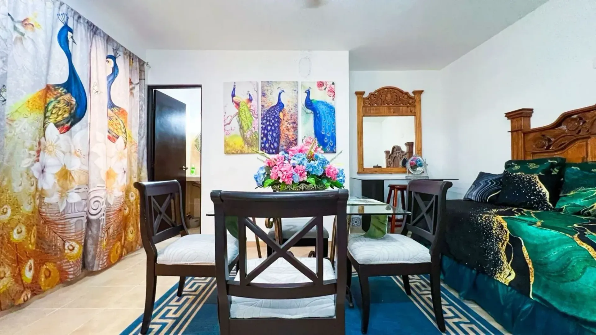 Dining area and bedroom with peacock decor, including a curtain, artwork, and bedding.
