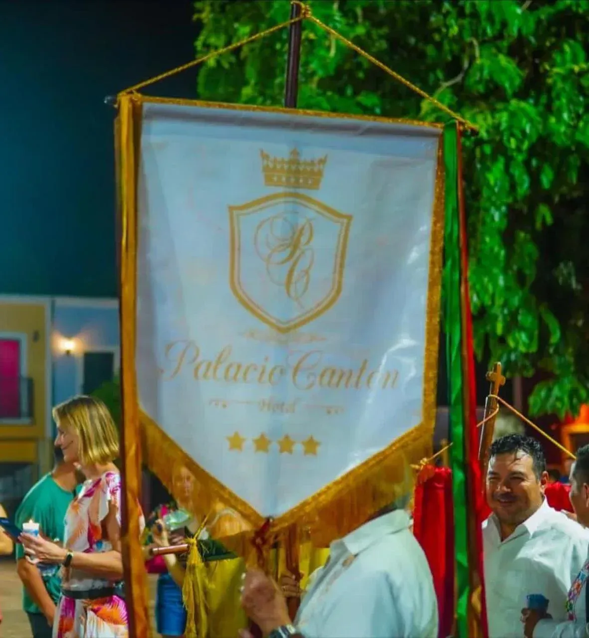 Banner for Palacio Cantón hotel with gold trim, held by people outdoors.