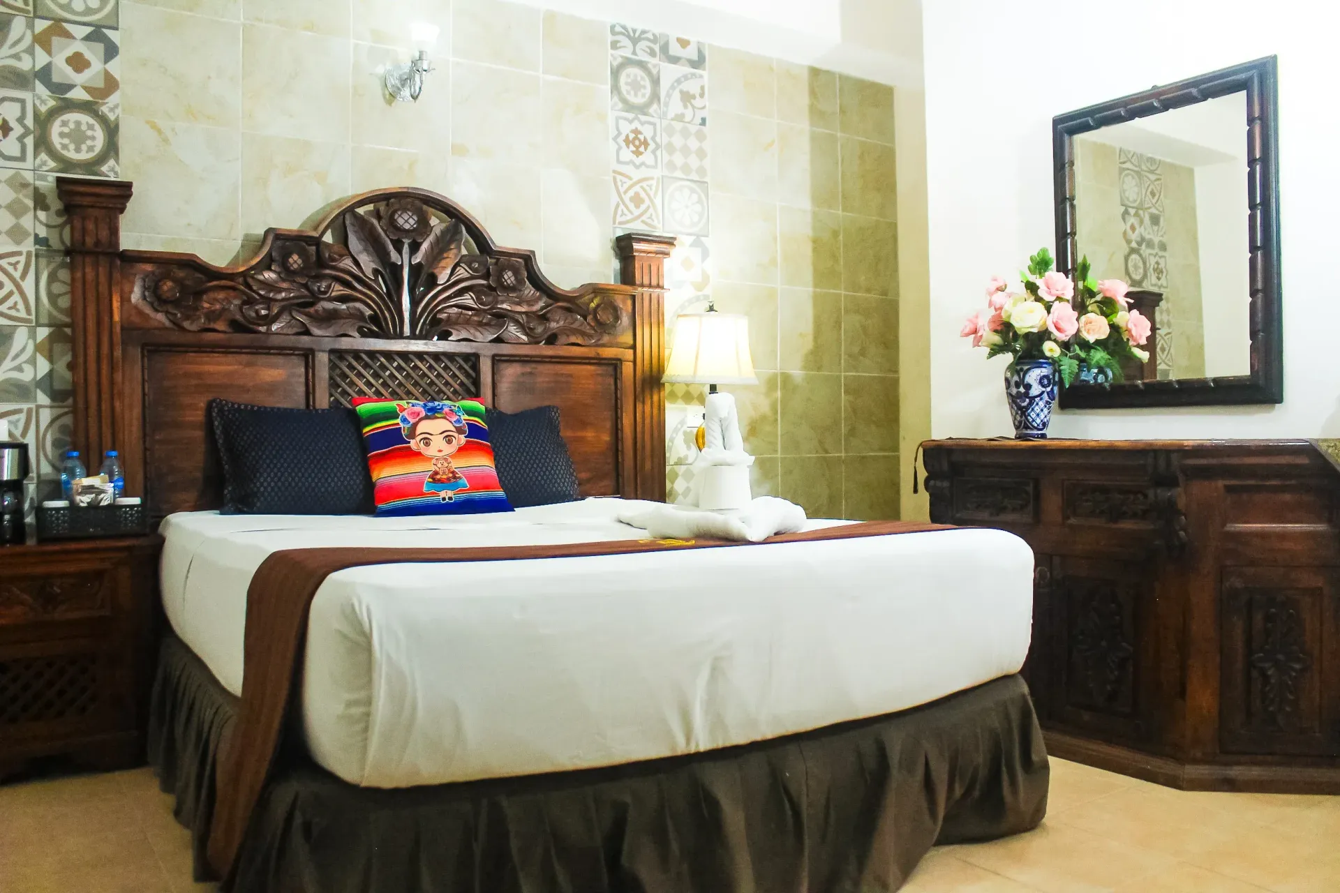 Habitación de hotel con una gran cama de madera y cómoda. Colores suaves.