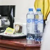 Cafetera, dos botellas de agua y un snack en una bandeja sobre una mesa de madera, al lado de una lámpara.