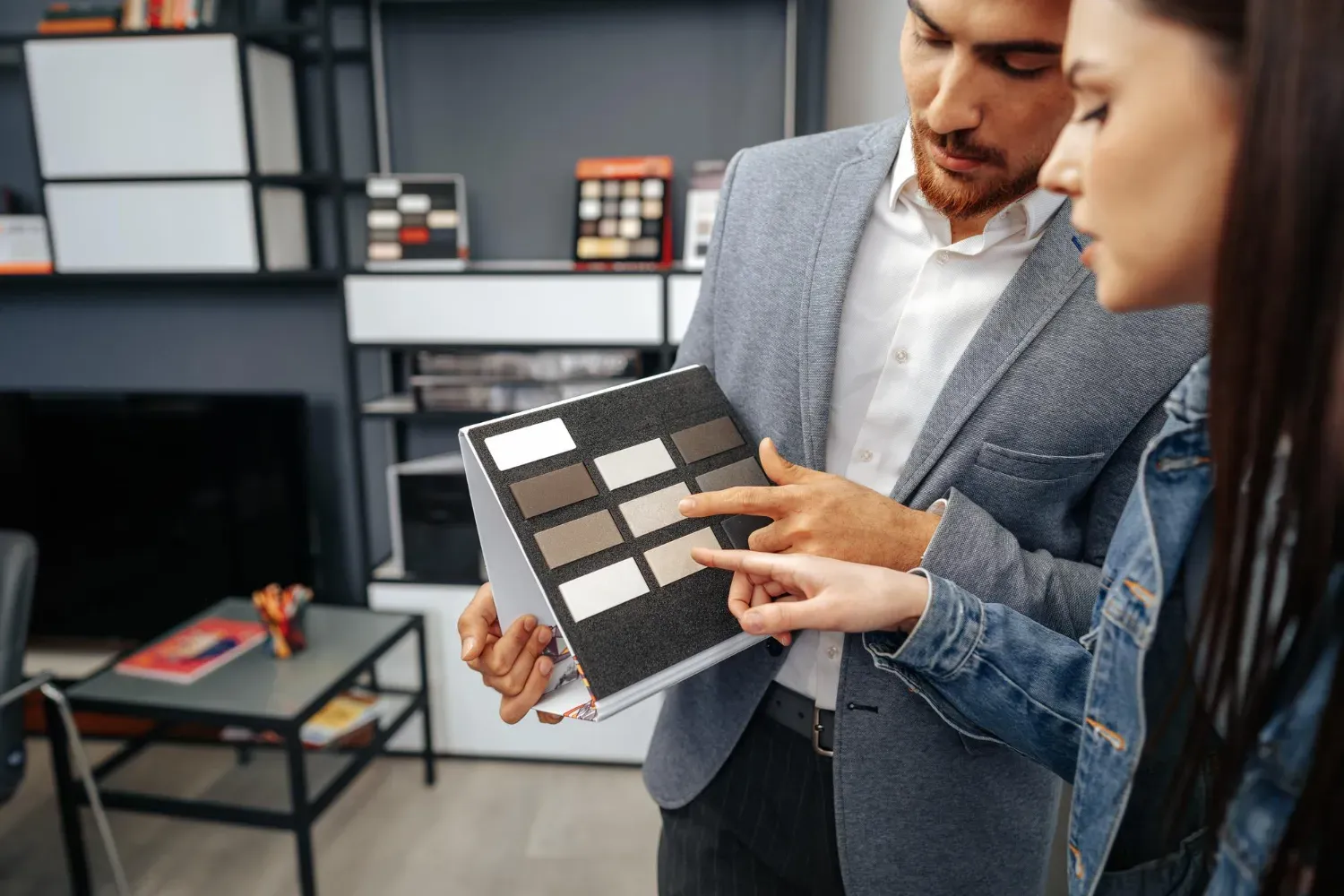Un homme et une femme regardent un échantillon de carrelage dans un salon.