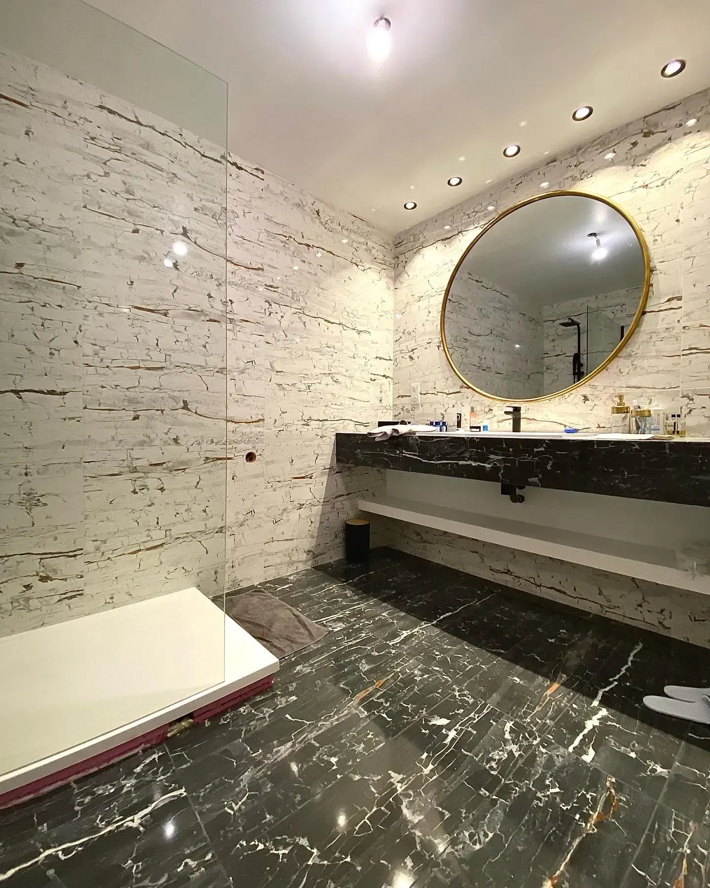 une salle de bain avec lavabo, miroir et douche à l'italienne.