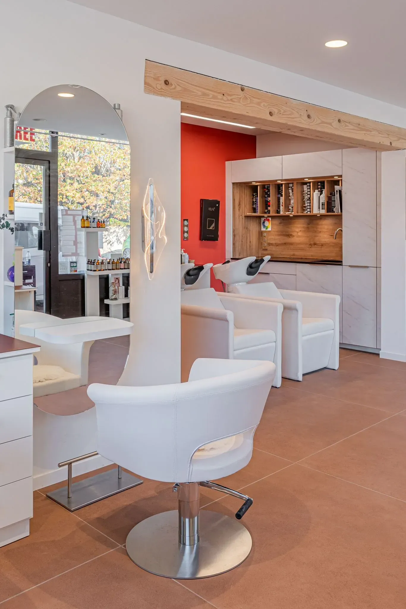 un salon de coiffure avec des chaises blanches et un grand miroir.