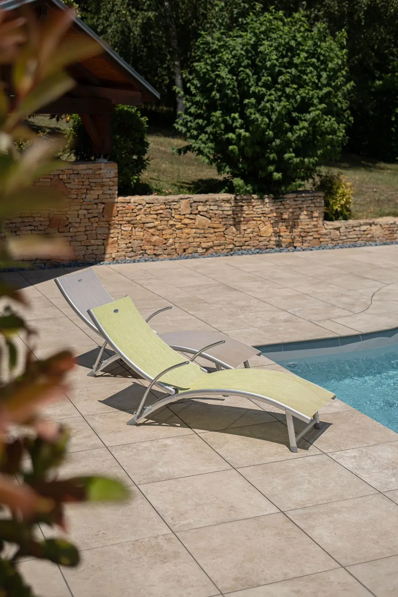 deux chaises longues vertes sont assises à côté d'une piscine.