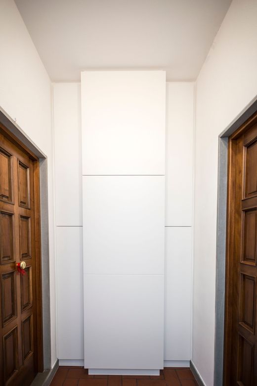 Un corridoio con due porte di legno e un mobile bianco.