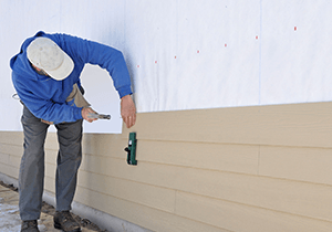 A man is installing siding on a wall.