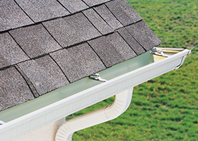 A white gutter is attached to the roof of a house