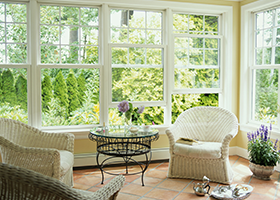 A living room with wicker furniture and lots of windows