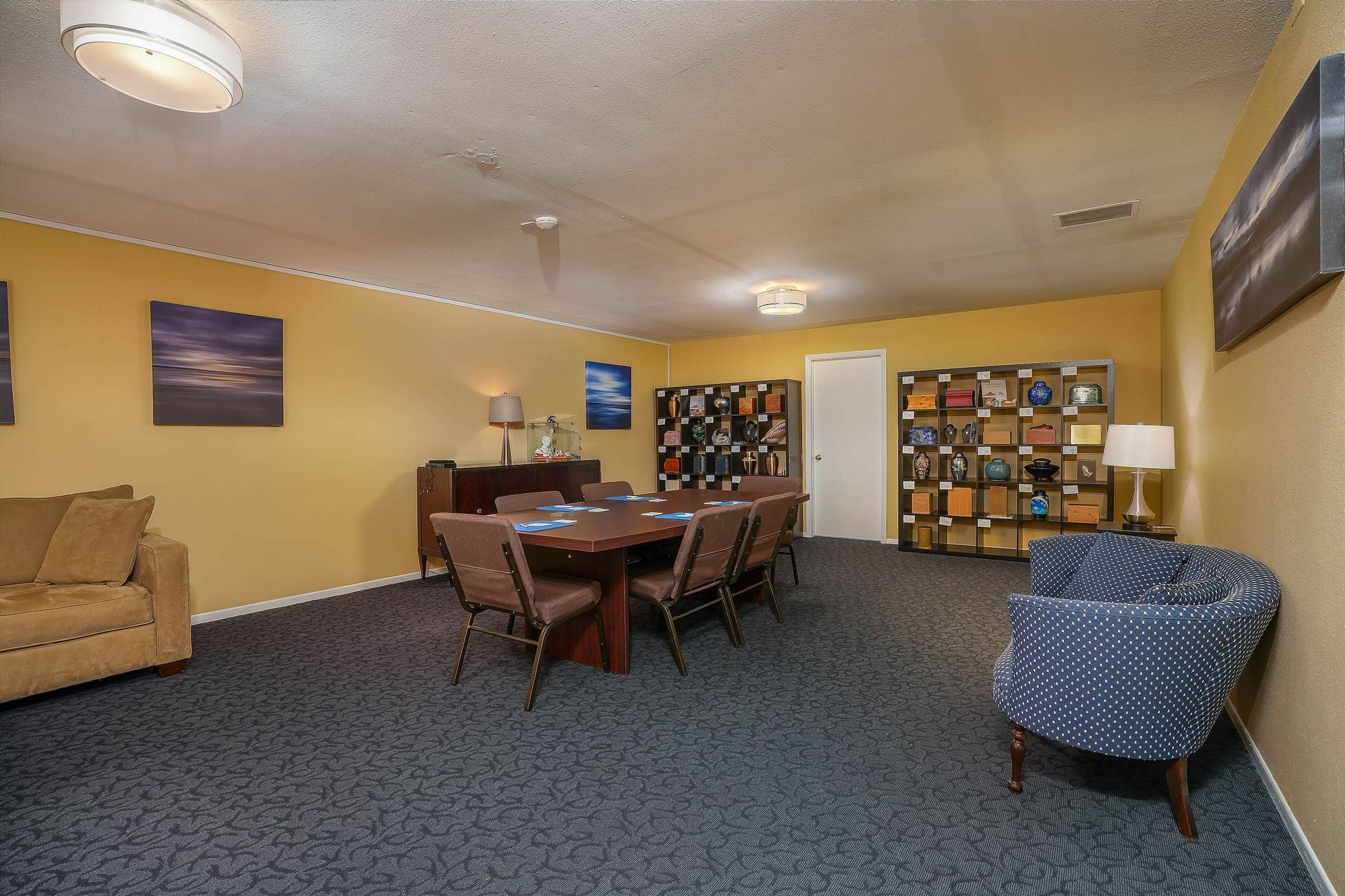 Cozy lounge with couches, chairs, tables, and wall art in a carpeted room