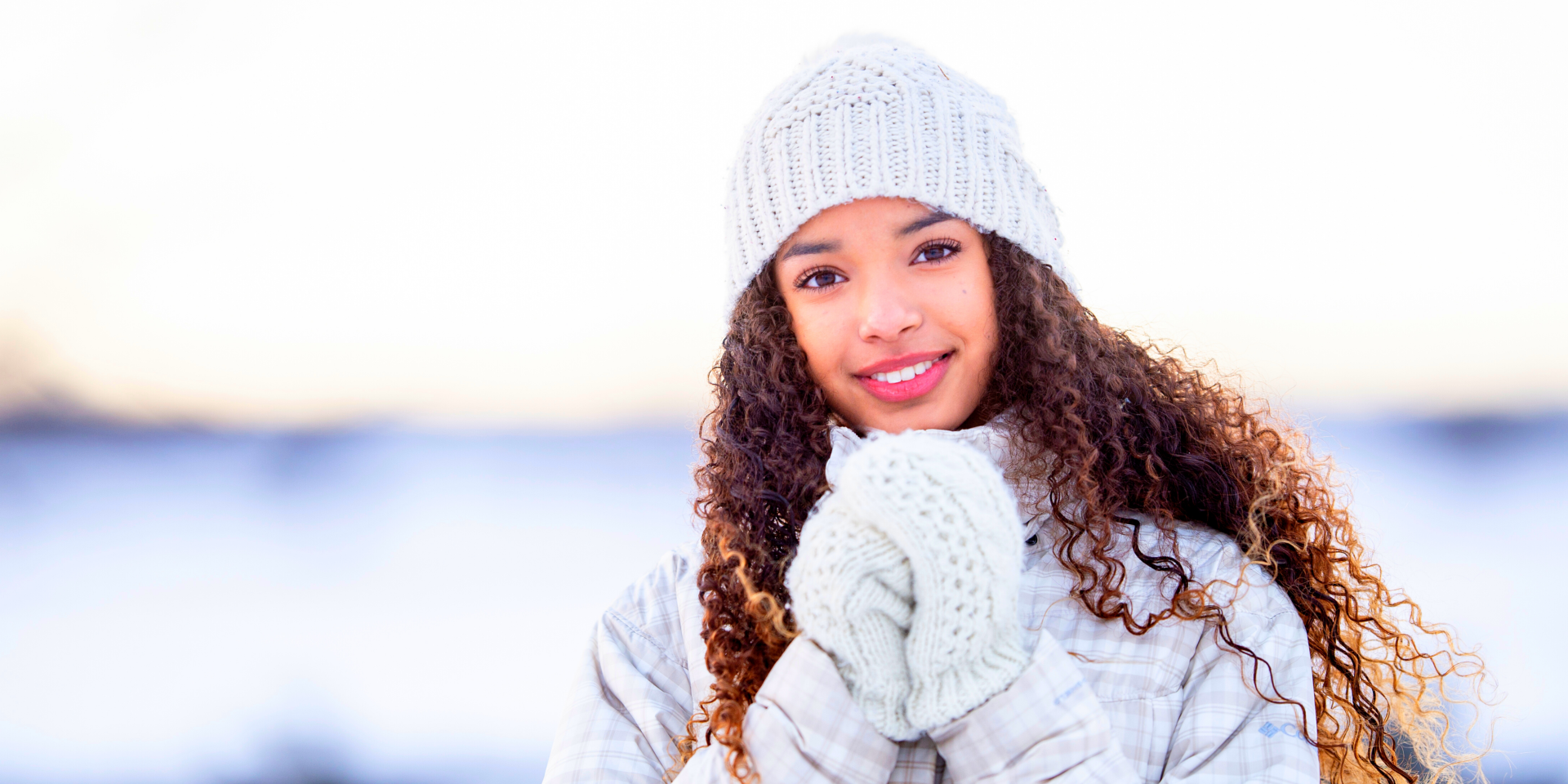 A woman wearing a hat and gloves is standing in the snow.