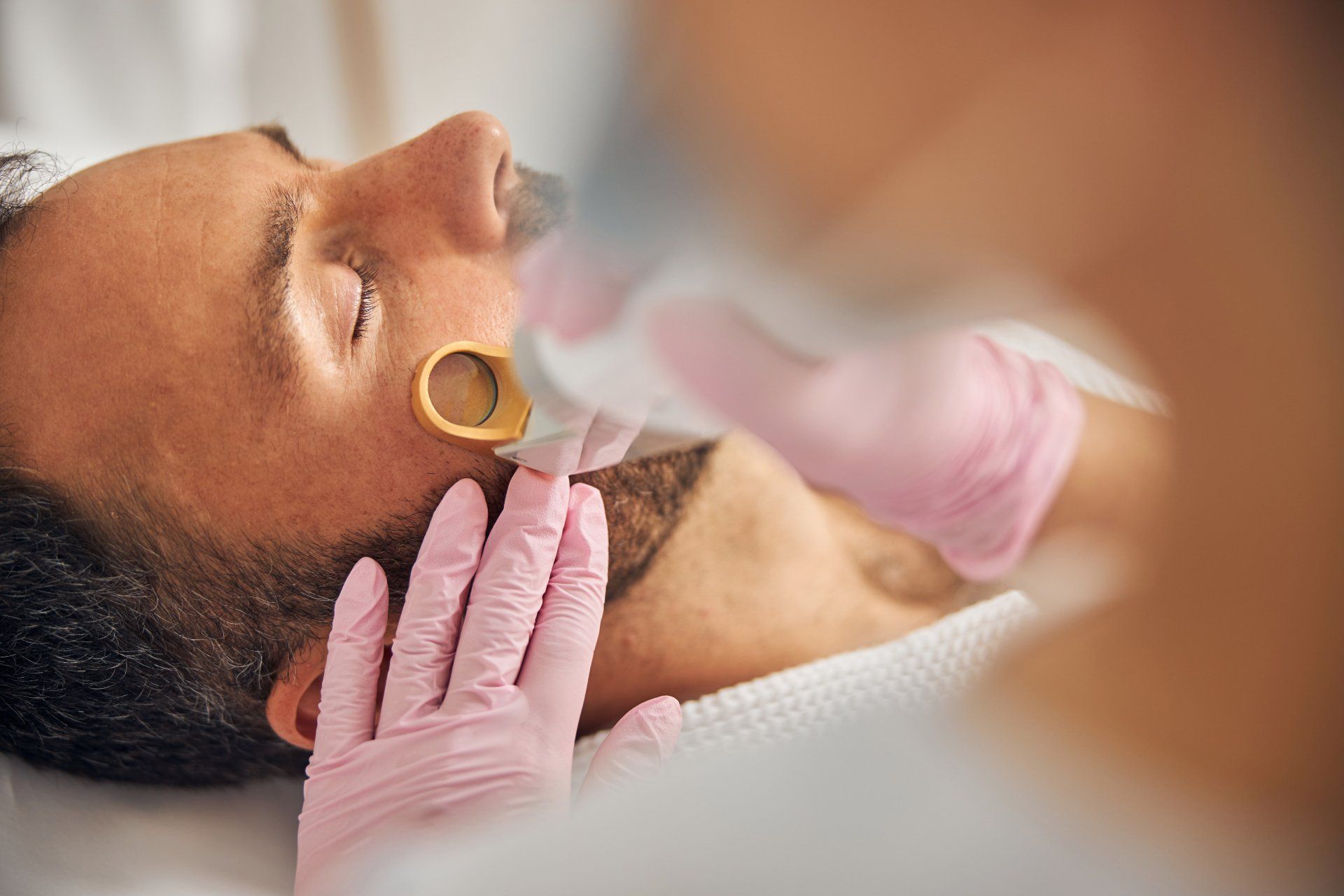 Close-up of a patient receiving a dental procedure with gloved hands and a suction tool