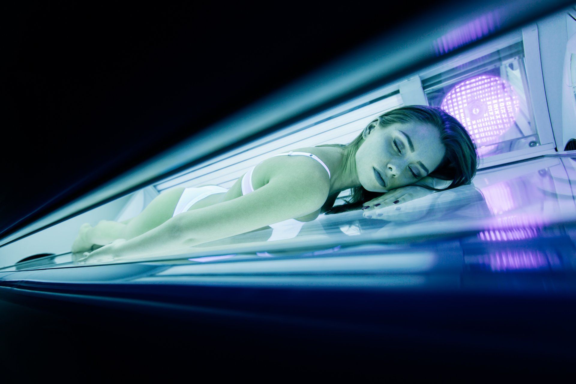 Person lying on a futuristic glowing platform under blue and purple lights