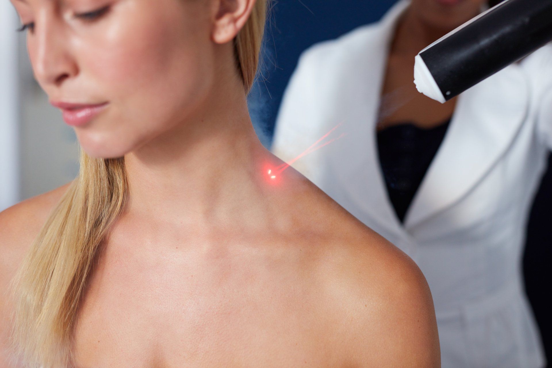 Doctor using a laser device on a woman's neck during a skin treatment, close-up view