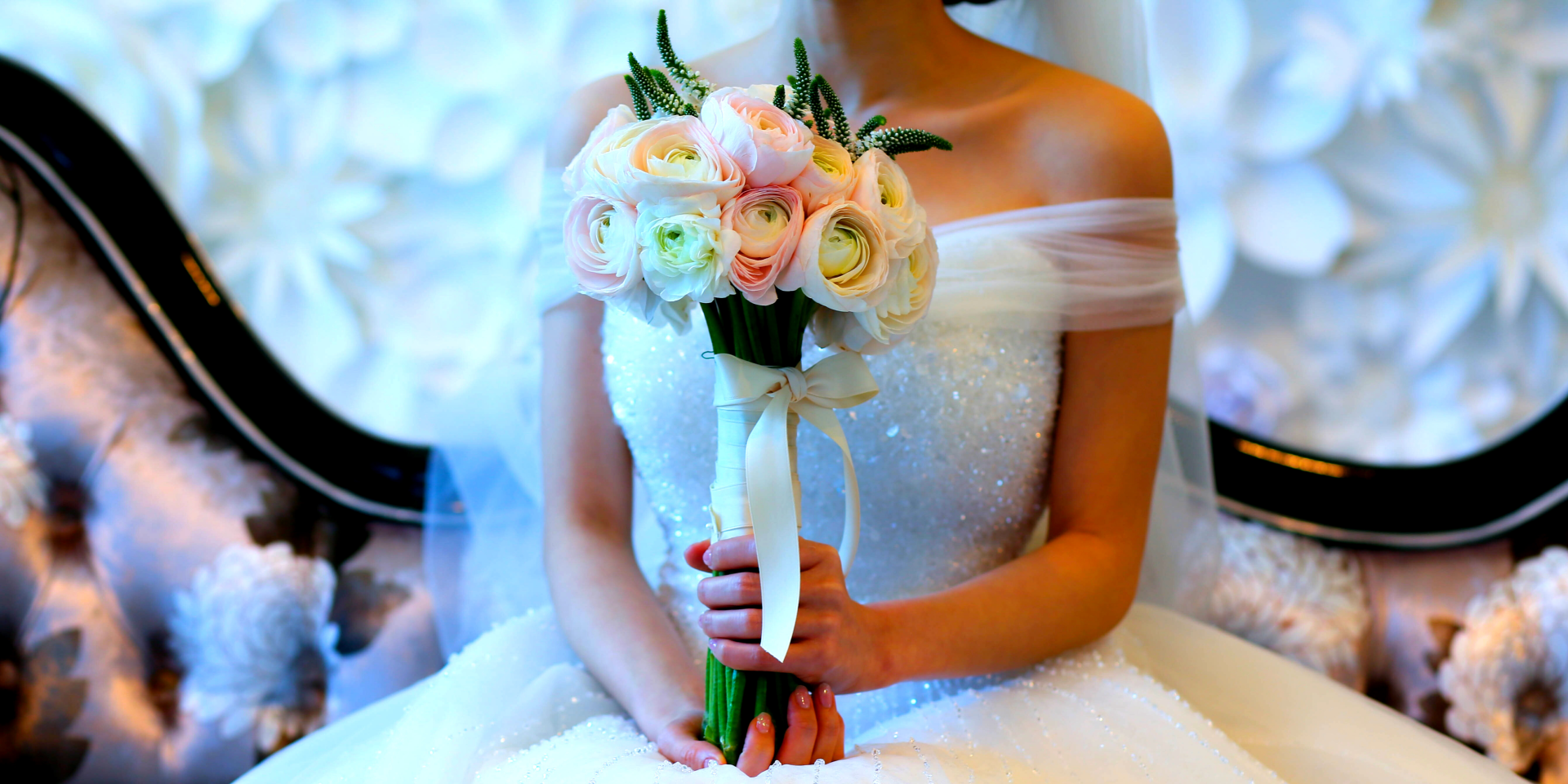 A bride in a wedding dress is holding a bouquet of flowers.