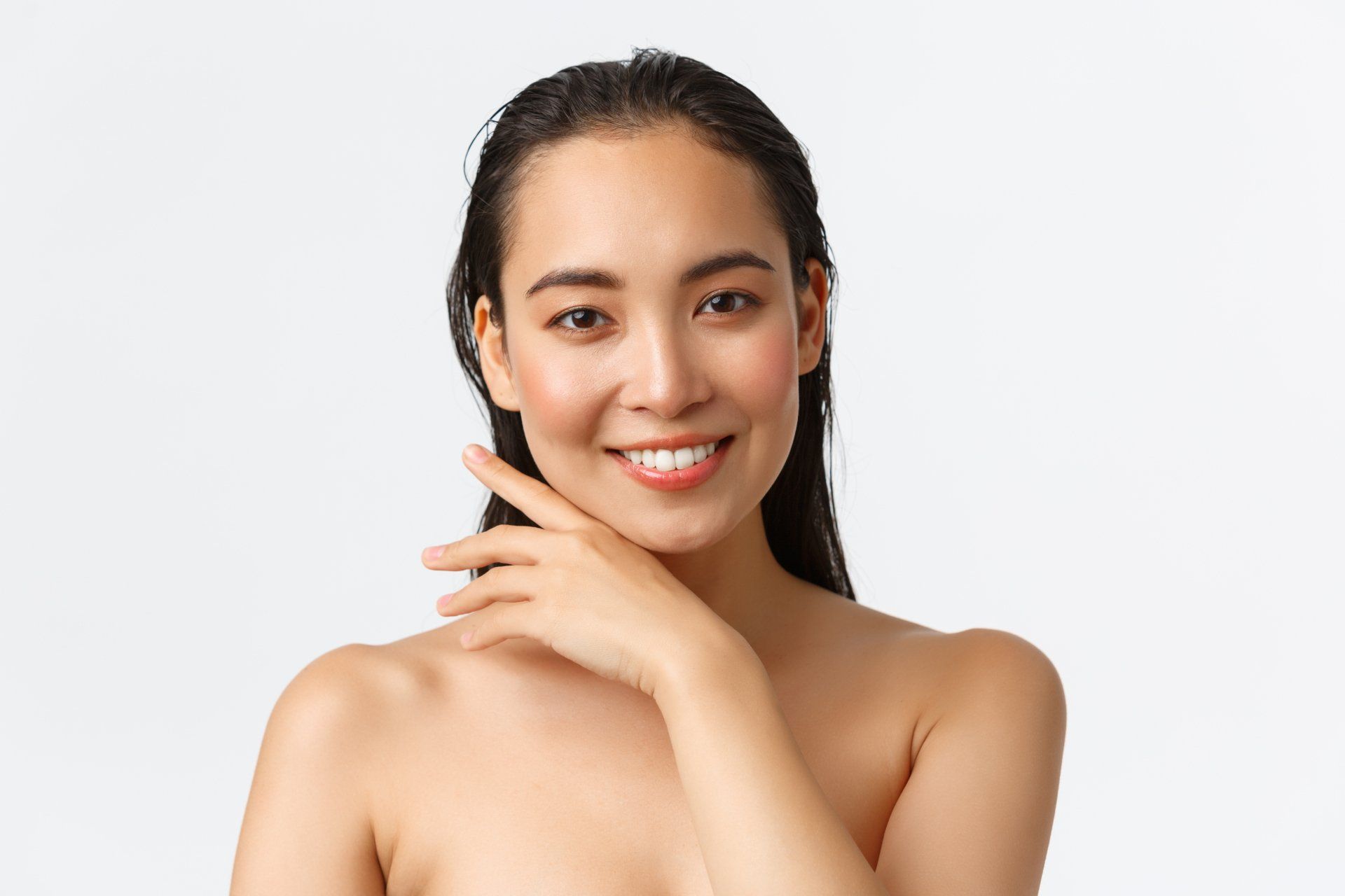 Smiling woman posing against a white background, hand near her chin.