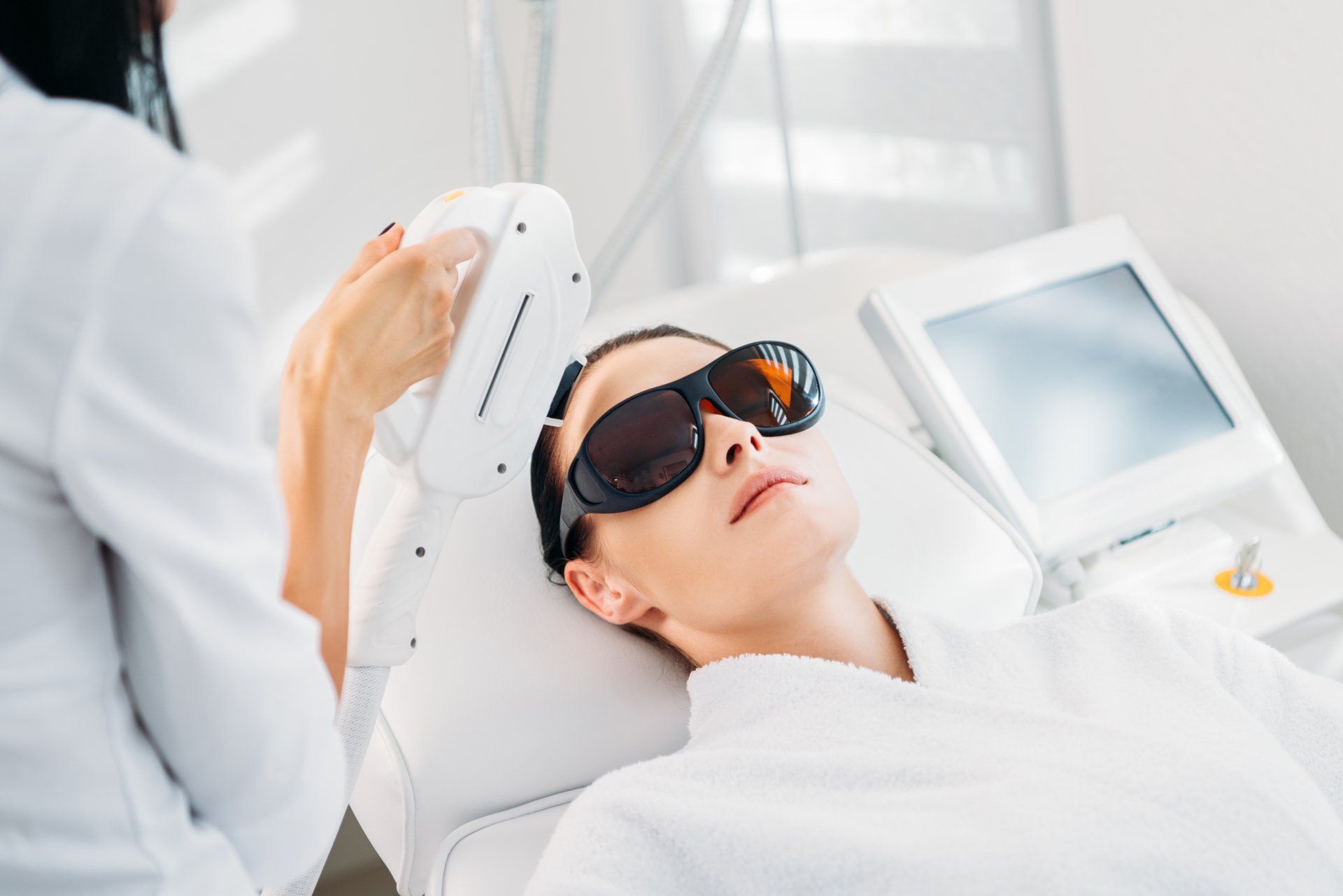 Person undergoing laser eye treatment while wearing protective goggles in a medical clinic