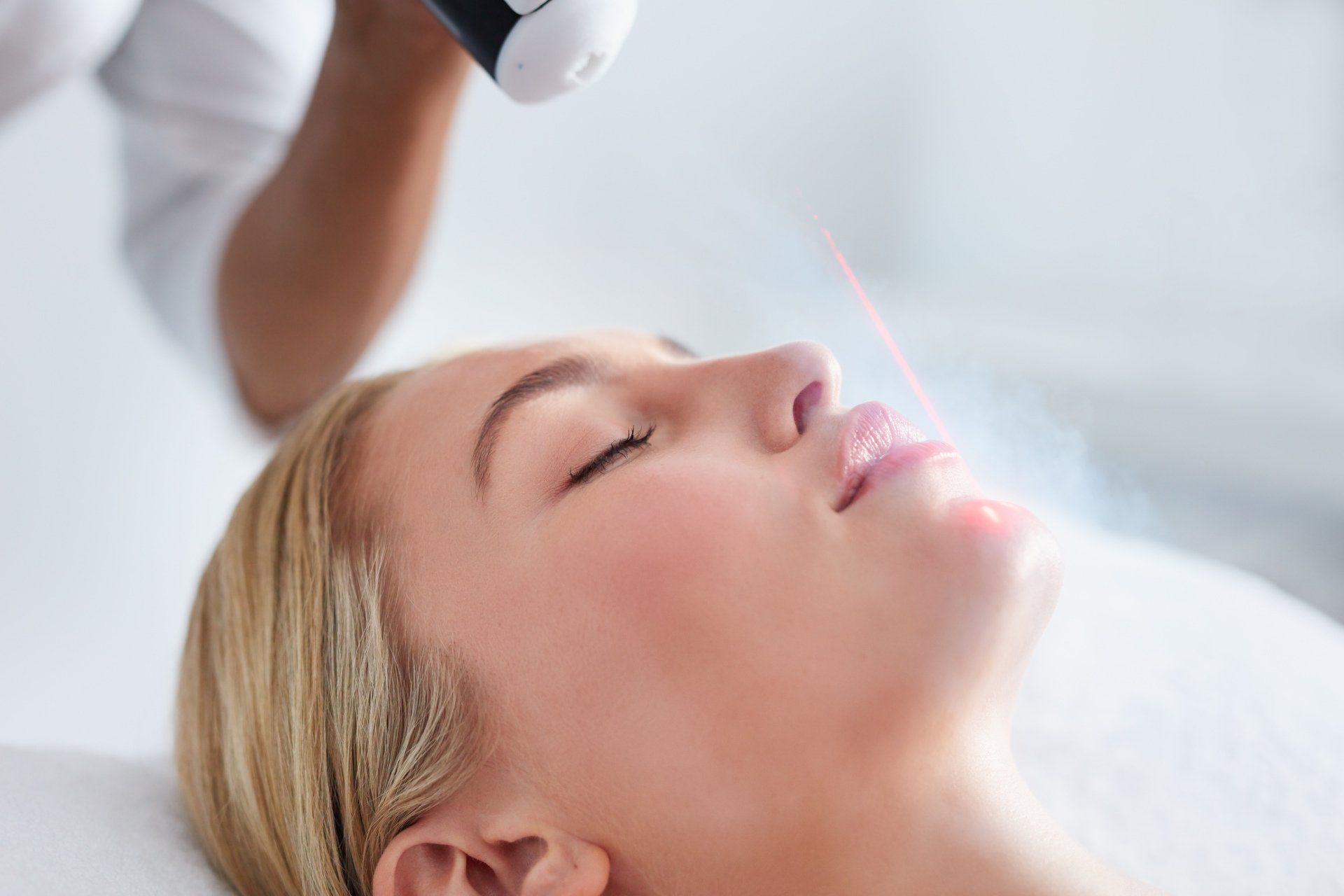 Woman receiving facial laser treatment with a device near her nose