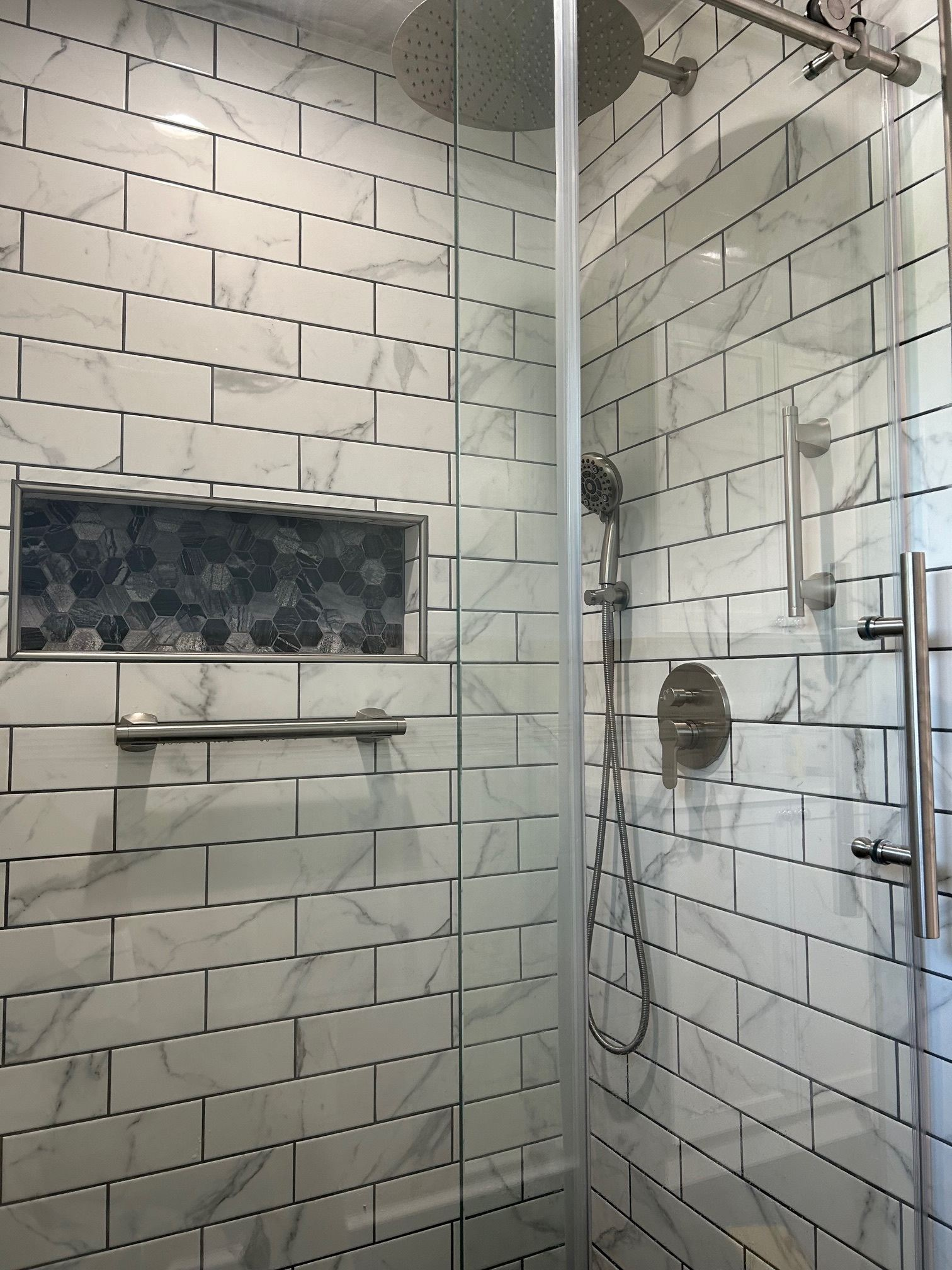 Glass shower with white subway tile walls and a built-in niche shelf