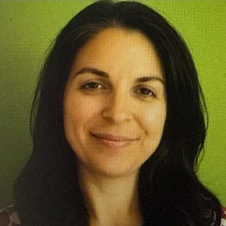 A woman with curly hair is smiling and wearing a green shirt.