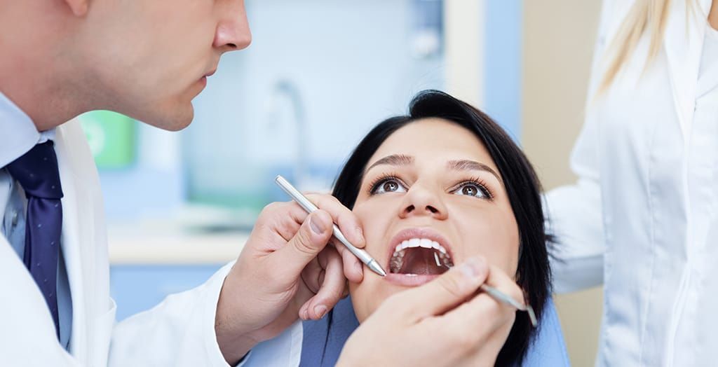 A woman is getting her teeth examined by a dentist. A woman is getting her teeth examined by a dentist.